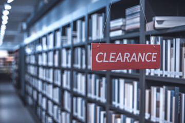 Red sign hanging in bookstore, saying "CLEARANCE" Bookshelves with blurred books in background Sale, discount, offer concept