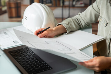 Architect holding and  working on a technichal blueprint project of new apartments in a multi-storey building .