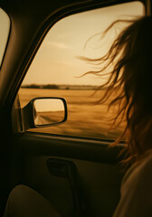Fototapeta premium Golden light streams into a moving car, framing wind-blown hair and endless fields beyond the window, evoking travel freedom.