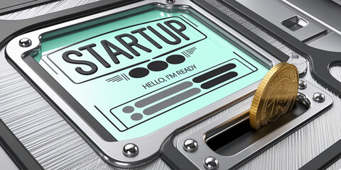 Metallic device displaying "STARTUP" with coin insertion slot, symbolizing business launch, investment, and financial growth