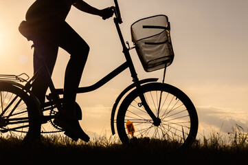 Close-up of a bicycle silhouette with an unrecognizable cyclist. Sunset background.