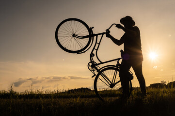 A silhouette of a cyclist holding and standing on the back wheel of a bicycle or bike. Sunset...