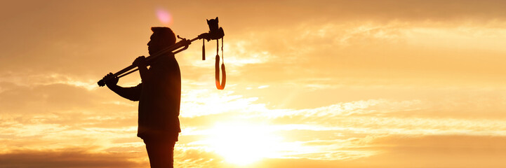 Silhouette of Man Carrying Tripod and Camera at Sunset in Wide Frame