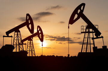 Silhouette of oil rigs or oil pump, equipment for oil field. Sunset background.