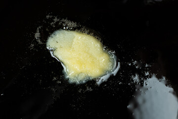 Ghee clarified butter melts in a cast iron skillet, cooking.