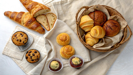 Top view of assorted bakery items including croissants, muffins, and bread rolls on a linen cloth