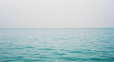 Obraz premium Turquoise Sea in Rain with Overcast Sky Serene Seascape of Ripples and Reflections