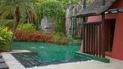Blurry tropical resort garden with lush greenery, pool, and a luxury outdoor atmosphere featuring defocused foliage, emphasizing relaxation and tranquility.