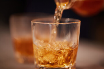 Whiskey pouring into glass with ice, creating refreshing drink