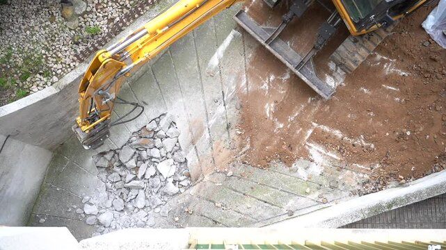 Construction equipment with a jackhammer breaks concrete, top view.