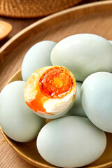 Salted duck eggs, a type of hand-pickled egg, are placed on a wooden table indoors