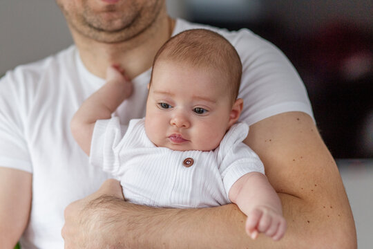 Father holds baby in cozy home setting while sharing a tender moment during the day
