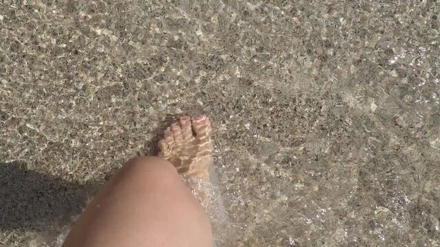 Young female feet standing on the beach and the sea waves washing them over. Sunset in background. vacation in the tropics, at sea. holidays