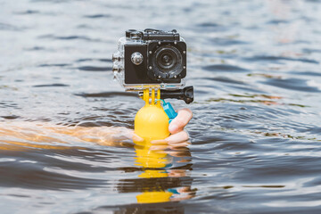 Action cameras with a waterproof case, in a girl's hand. Close-up water background.