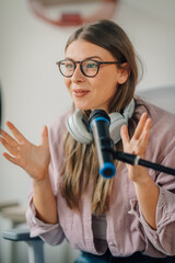 Young woman recording a podcast using headphones and microphone