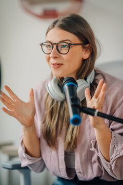 Young woman recording a podcast using headphones and microphone