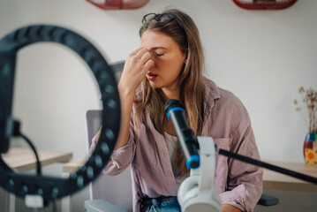 Influencer feeling stressed while recording a podcast in home studio