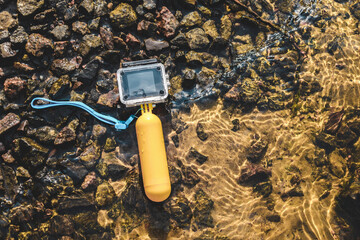 Waterproof action camera lies on the seashore with clear water. Rest and vacation time.