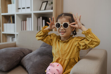 a cut little girl is happy with her beautiful sunglasses on the sofa in the living room at home,...