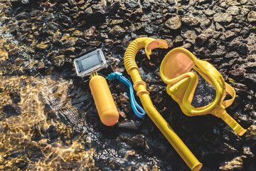 Waterproof action camera with a mask and snorkel on a rocky shore near the water. Swimming ban...