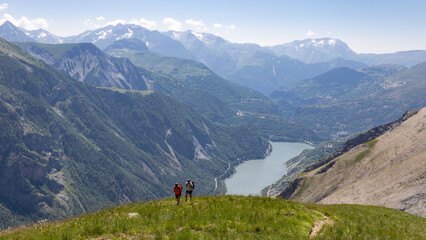 Fototapeta premium randonneur arrivant sur le plateau d'Emparis depuis vallée du Ferrand et le lac de Chambon dans les Alpes de l'Isère en été
