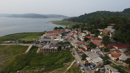 An aerial view captures the peaceful charm of a quaint village nestled by the tranquil lake, showcasing the harmonious blend of nature and rural architecture.