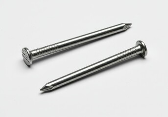 Close-up of two shiny metal nails with flat heads and pointed tips on a white surface