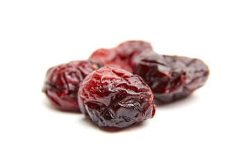Four dried cranberries with wrinkled skins and deep red tones arranged on a clean white background, showing glossy texture and rich color variation