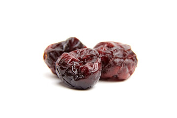 Trio of dried cranberries placed on white background with rich dark red hues, textured wrinkled skin, and glossy surface details captured in macro
