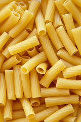 Detailed macro view of raw tortiglioni pasta showing cylindrical shape and ribbed texture in bright natural light.