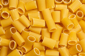 Pile of uncooked mezzi rigatoni pasta tubes with ridged texture and short cylindrical shape captured in detailed close-up
