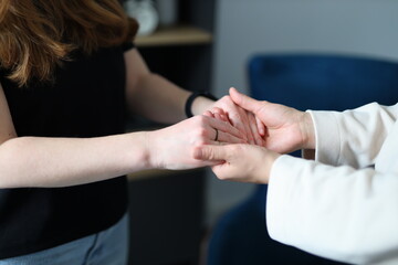 Caucasian female adults holding hands for comfort and support