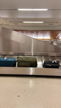 Airport conveyor belt or luggage carousal with different suitcases and bags. Terminal with landing flights check in bags arriving. Phone camera pov user generated style content from amateur traveler