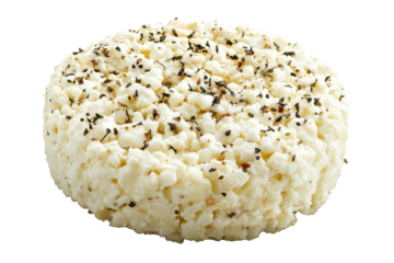 Crumbled cheese wheel speckled with spices atop a black expanse
