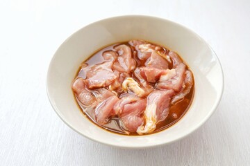 Marinated pork in white ceramic bowl on white background