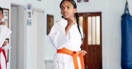 Girl, learning and karate student in dojo for combat, kids tournament or sports training with...