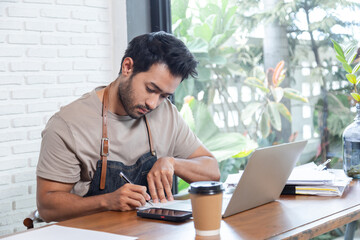 Attractive barista male or employee concentrate on stacks of tax declaration bills, restaurant...