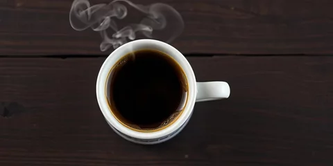 Fototapete Rund Steaming cup of coffee on dark wood grain background, surface, brew © chonlada