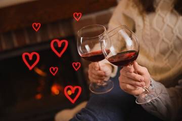 Couple with glasses of red wine indoors, closeup. Drawn hearts near them