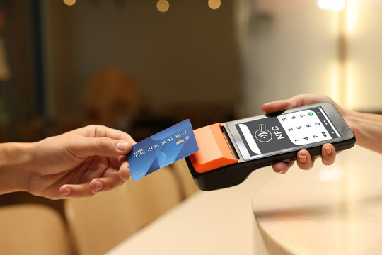 Payment terminal with NFC system. Client using credit card to pay for service indoors, closeup