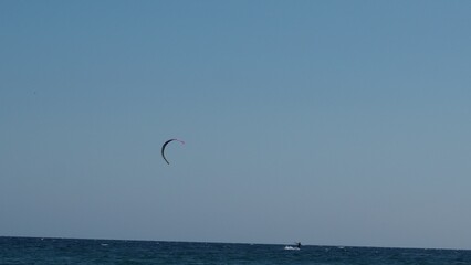 Parachuter, skydiver jumping and skydiving in parachute of yellow white black colours on parachuting cup, extreme sport active recreation on the coast sea. paragliding