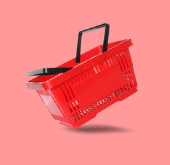 Red shopping basket in air on salmon color background