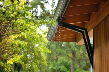 Rain chain falling from modern eave near garage --ar 3:2 --v 7 Job ID: a124ba99-cd16-4c64-b00c-947caefa8a74