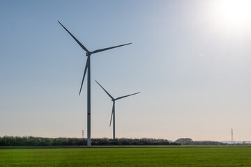 Two wind turbines are standing in a field with a clear blue sky