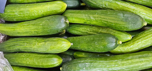 A stack of fresh green cucumbers arranged closely with visible skin texture and minor stem remnants on some ends Spain;