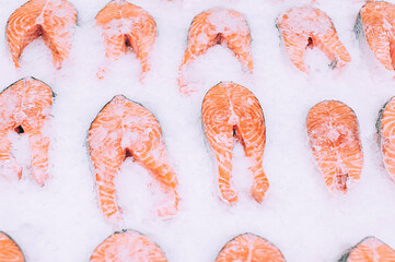 Rows of fresh salmon fillets on ice at fish market.