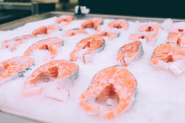 Fresh salmon fillets and pieces on ice, close-up.