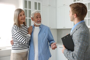 Obraz premium Real estate agent with clipboard working with couple in kitchen