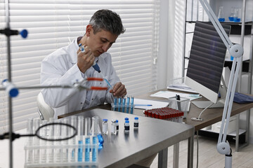 Scientist with micropipette and test tubes working in laboratory