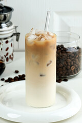 Homemade Ice Coffee Milk in a Tall Glass with Milk Cream, Ice Cube and Dark Beans on the Back.